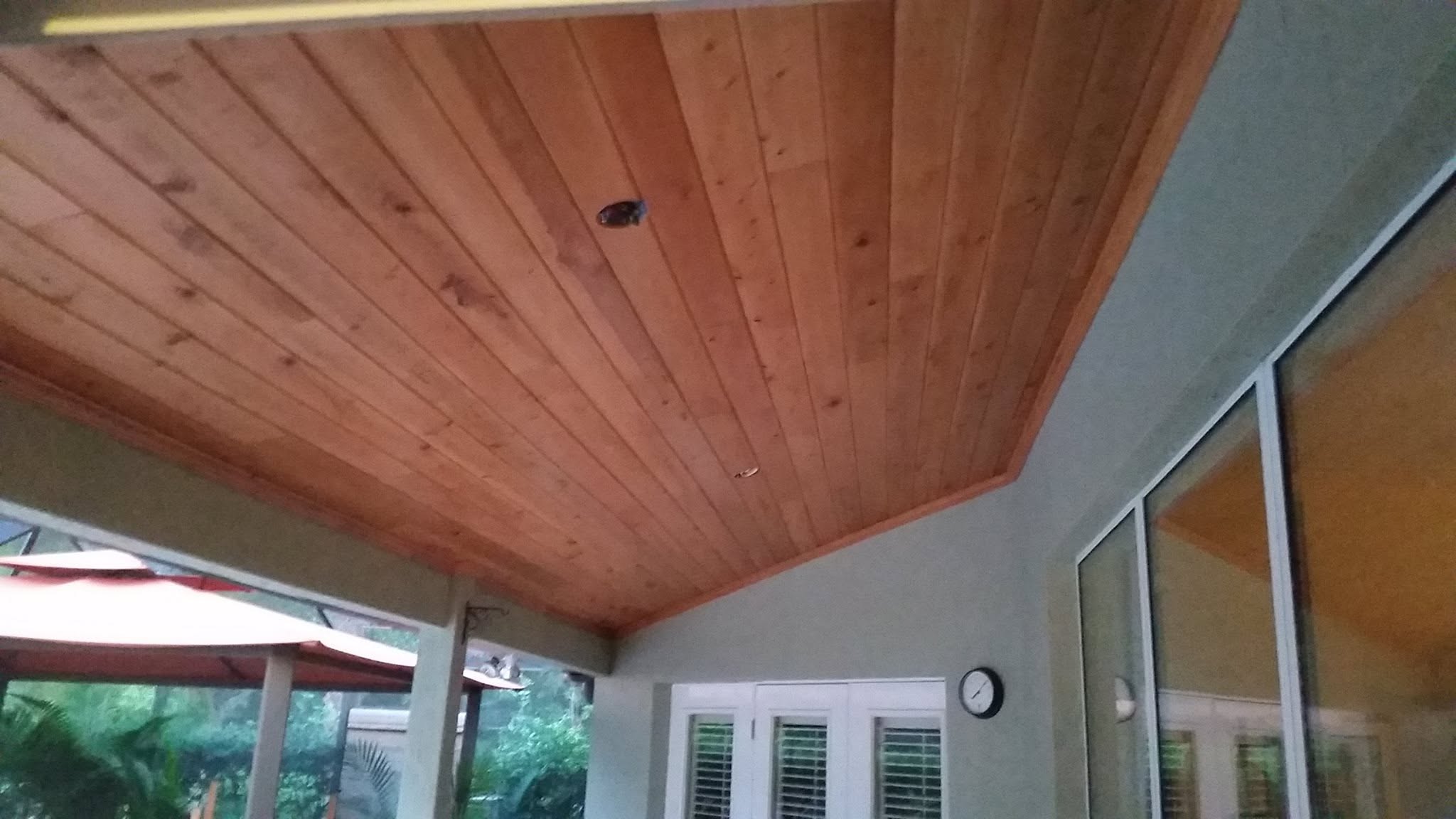 Cypress tongue-and-groove ceiling with finished wood trim on a covered porch