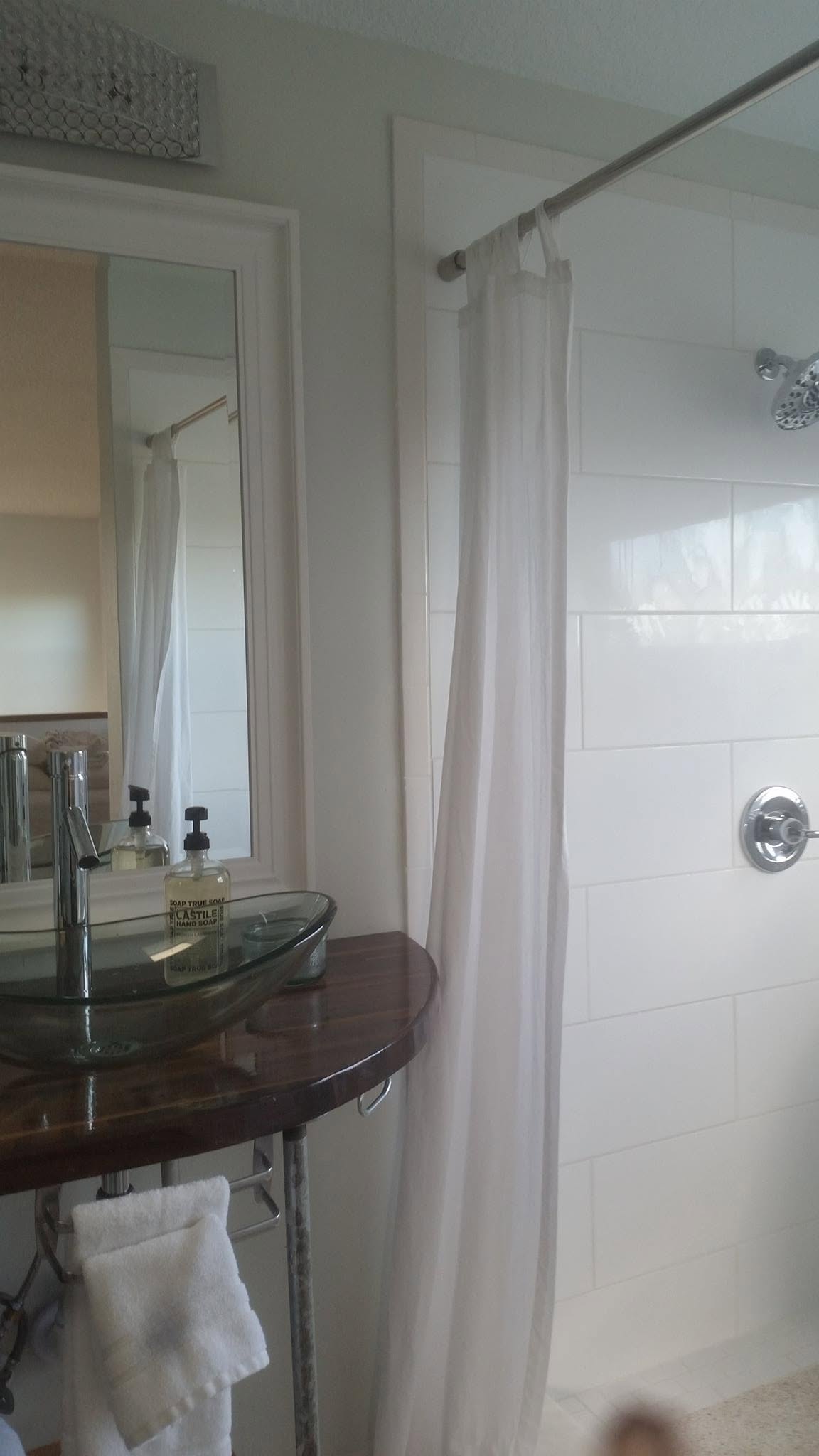 Bathroom with a glass vessel sink, wood vanity, tiled shower, and curtain